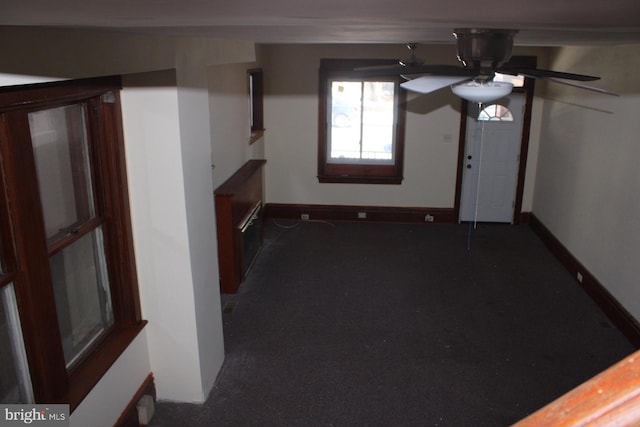 interior space featuring ceiling fan and dark colored carpet