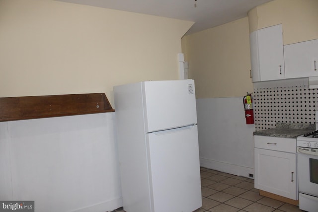 kitchen featuring tasteful backsplash, light tile patterned floors, white appliances, and white cabinets