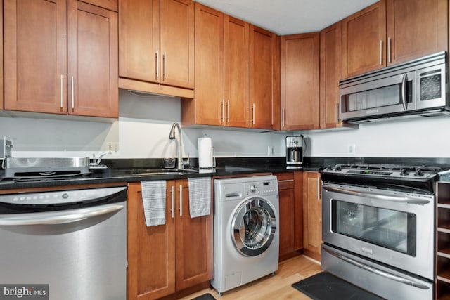 kitchen featuring sink, light wood-type flooring, washer / dryer, and stainless steel appliances