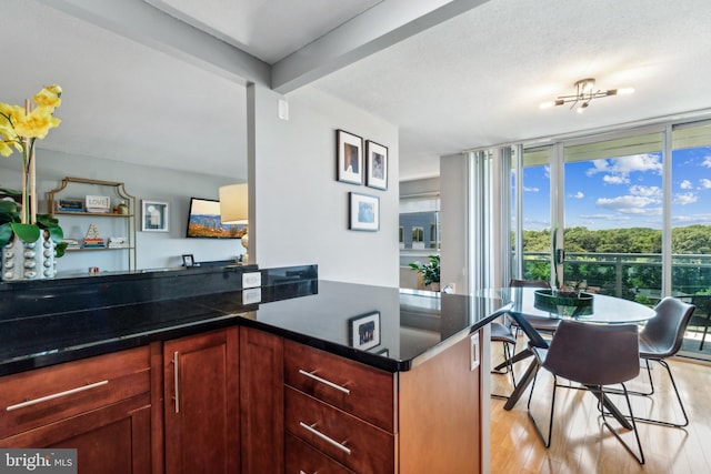 kitchen with a textured ceiling, beamed ceiling, kitchen peninsula, light wood-type flooring, and floor to ceiling windows