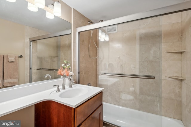 bathroom featuring combined bath / shower with glass door and vanity