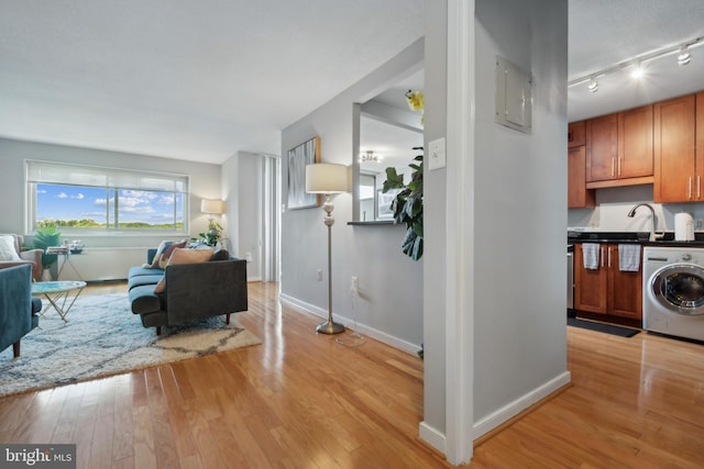 living room featuring washer / dryer, rail lighting, and light hardwood / wood-style floors