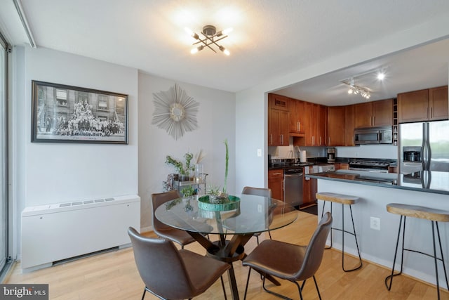 dining area featuring light hardwood / wood-style floors, radiator, and an inviting chandelier