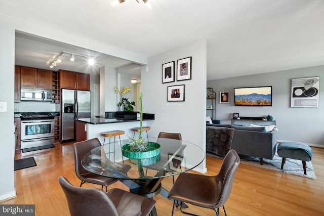 dining area with rail lighting and light hardwood / wood-style flooring