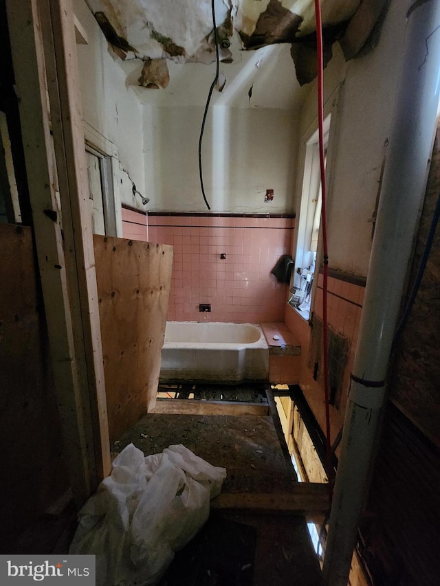 bathroom featuring a bath and tile walls