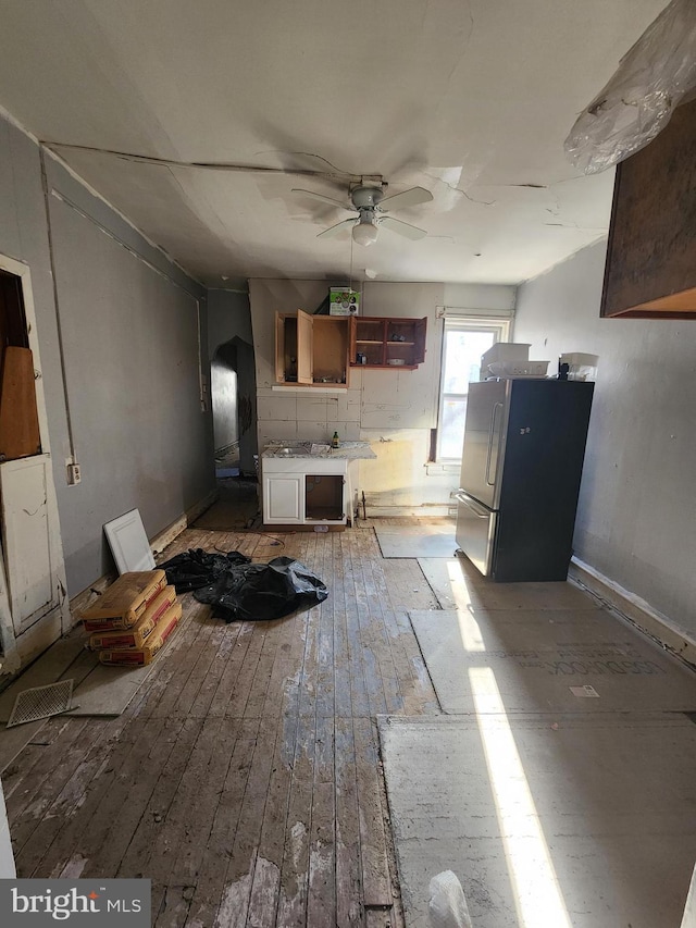 interior space with white cabinetry, ceiling fan, stainless steel fridge, and light wood-type flooring