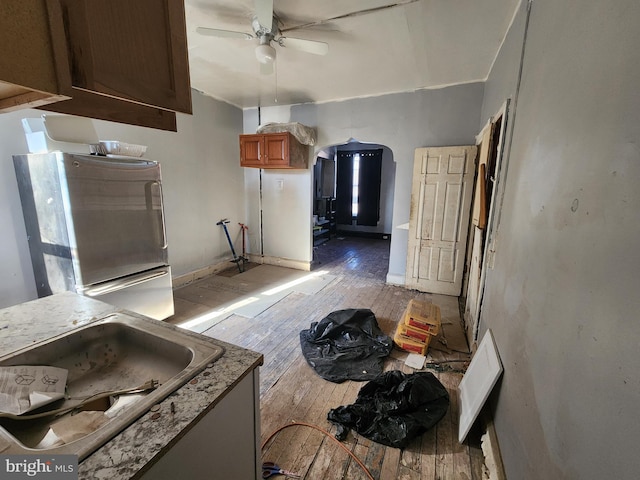 kitchen with sink, light hardwood / wood-style floors, ceiling fan, and refrigerator