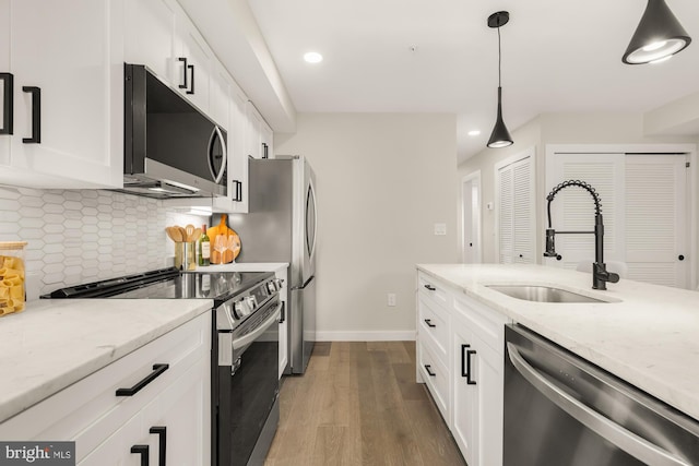 kitchen featuring white cabinets, hanging light fixtures, appliances with stainless steel finishes, and light stone counters