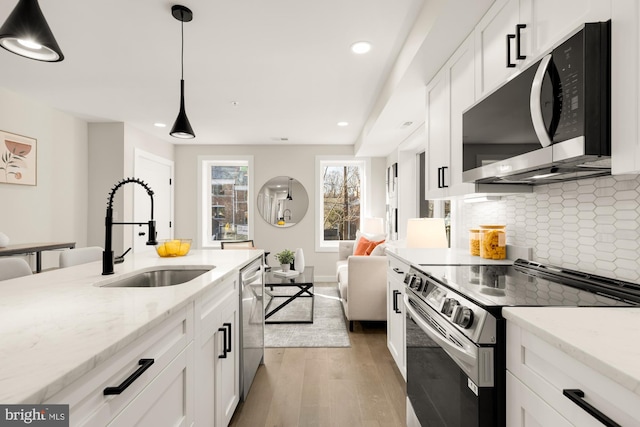 kitchen with sink, light stone counters, decorative light fixtures, and stainless steel appliances