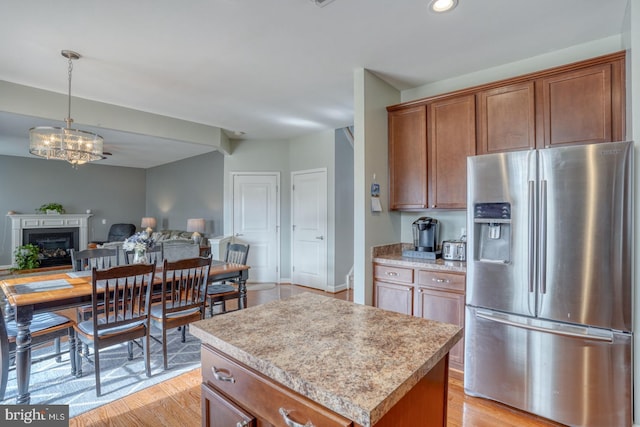 kitchen with light countertops, open floor plan, stainless steel fridge, and light wood finished floors