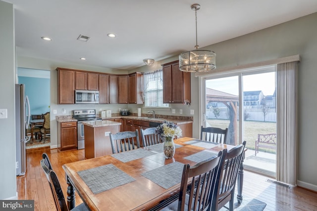 kitchen featuring appliances with stainless steel finishes, visible vents, light wood finished floors, and an inviting chandelier