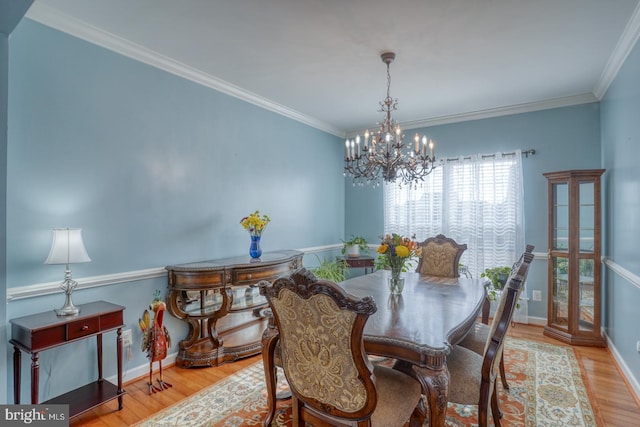 dining room featuring baseboards, a notable chandelier, wood finished floors, and crown molding