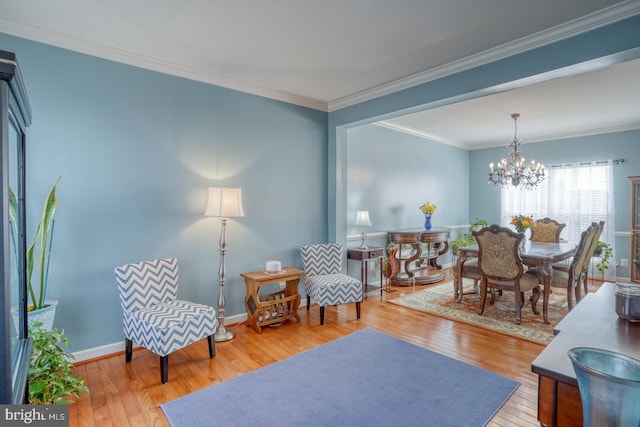 sitting room featuring wood-type flooring, crown molding, baseboards, and an inviting chandelier