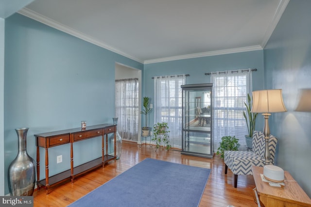 sitting room with ornamental molding and wood finished floors