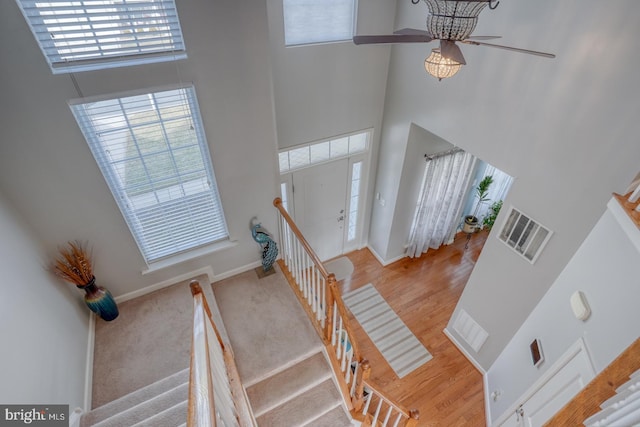 entrance foyer with a towering ceiling, stairs, visible vents, and a wealth of natural light