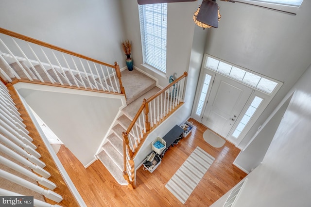 foyer entrance featuring stairs, wood finished floors, a towering ceiling, and baseboards