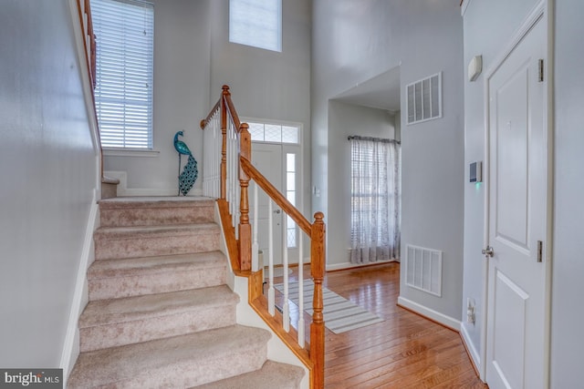 stairway with a wealth of natural light, hardwood / wood-style flooring, and visible vents