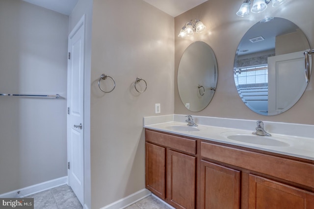 bathroom featuring double vanity, baseboards, a sink, and tile patterned floors