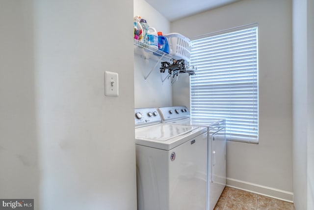 clothes washing area featuring light tile patterned floors, laundry area, washing machine and dryer, and baseboards