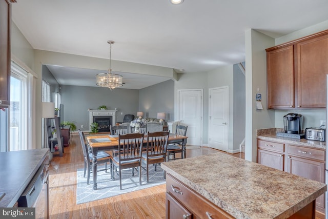 dining space with light wood-type flooring, an inviting chandelier, and a fireplace