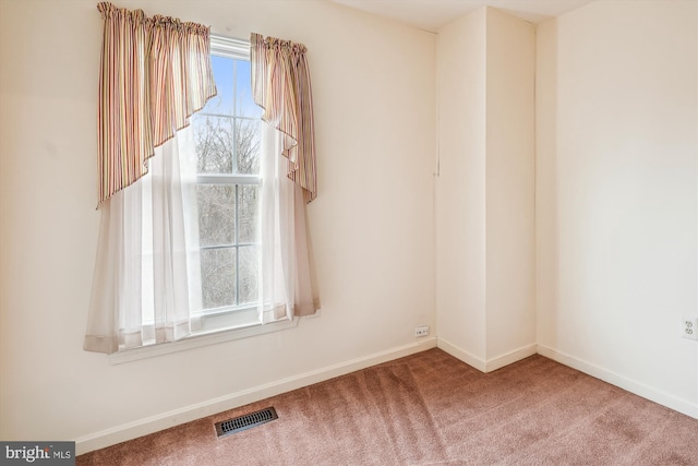 spare room featuring carpet floors, visible vents, and baseboards