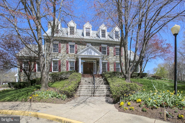 colonial home with stone siding and a front lawn