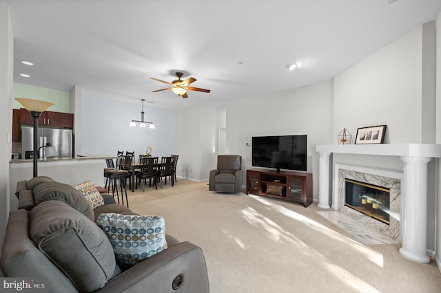 living room featuring ceiling fan, light colored carpet, and a high end fireplace