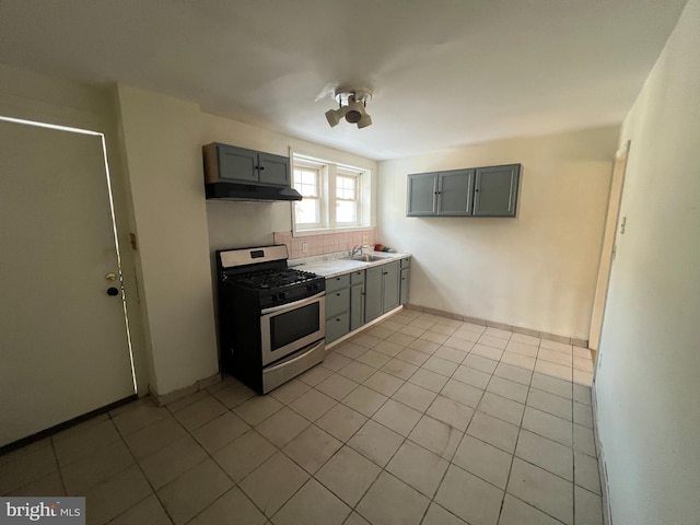 kitchen featuring stainless steel range with gas stovetop, gray cabinets, and light tile patterned floors