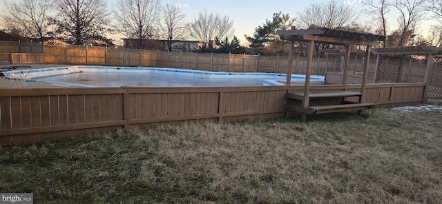 pool at dusk featuring a lawn