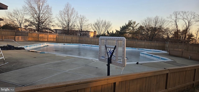 pool at dusk with a patio area