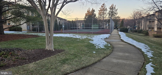 view of community featuring tennis court and a lawn