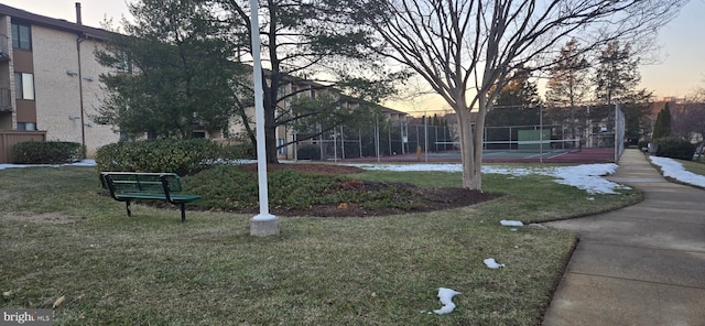 view of home's community featuring tennis court and a lawn