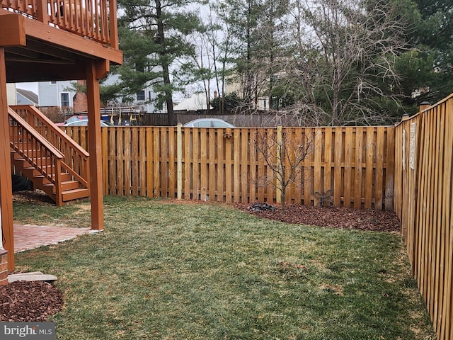 view of yard featuring a fenced backyard and stairs