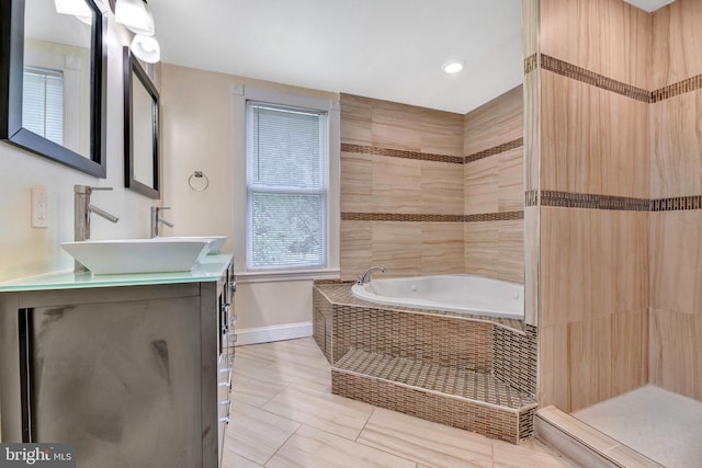 bathroom with vanity, a relaxing tiled tub, and tile patterned flooring