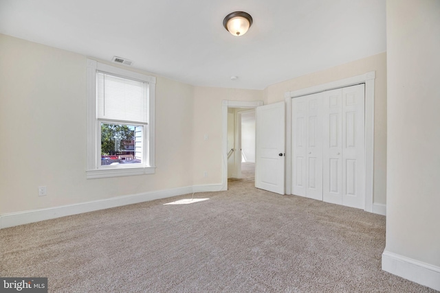 unfurnished bedroom featuring light carpet and a closet