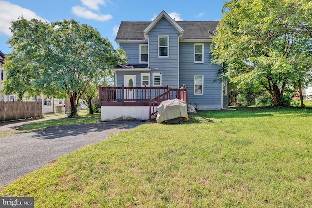 rear view of property featuring a deck and a lawn