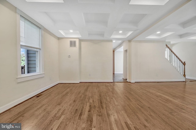 unfurnished room with coffered ceiling, light wood-type flooring, beamed ceiling, and built in features