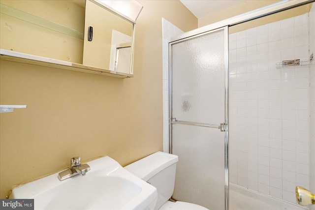 bathroom featuring sink, toilet, and a shower with door