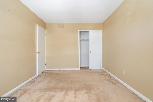 unfurnished bedroom with light carpet and a closet