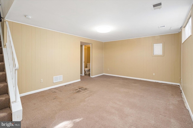 carpeted spare room with wooden walls