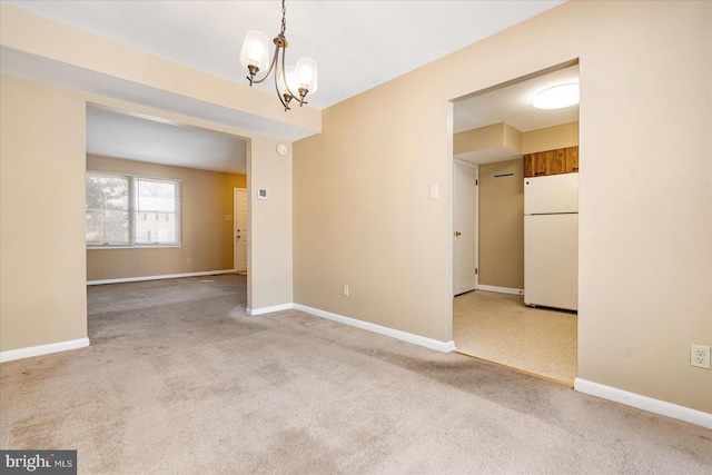 empty room with light colored carpet and a notable chandelier