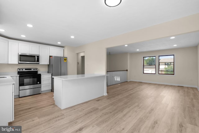 kitchen with light wood-type flooring, a center island, white cabinets, and appliances with stainless steel finishes