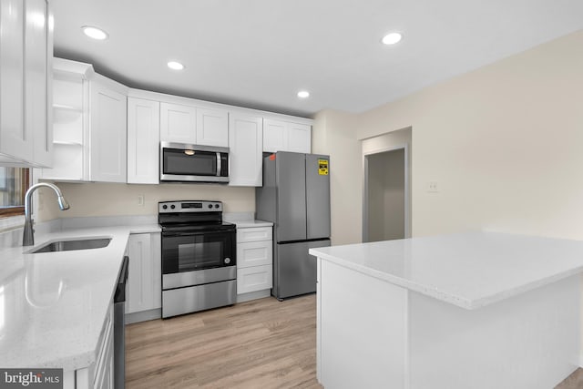 kitchen featuring sink, light stone counters, stainless steel appliances, light hardwood / wood-style floors, and white cabinets