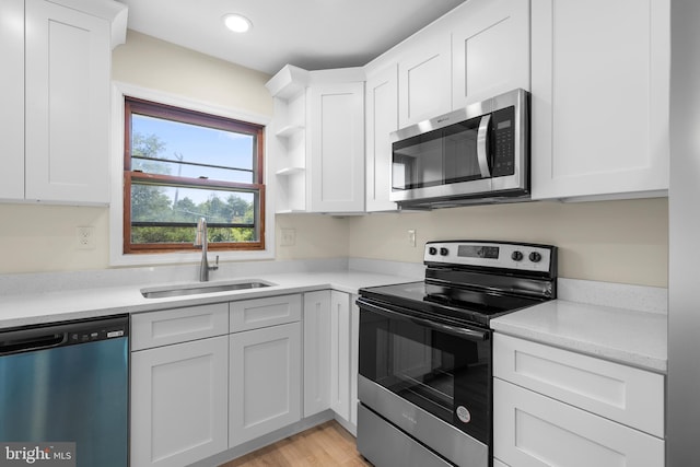 kitchen with light wood-type flooring, stainless steel appliances, sink, and white cabinets