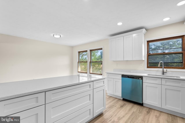 kitchen with white cabinetry, sink, stainless steel dishwasher, light stone counters, and light wood-type flooring