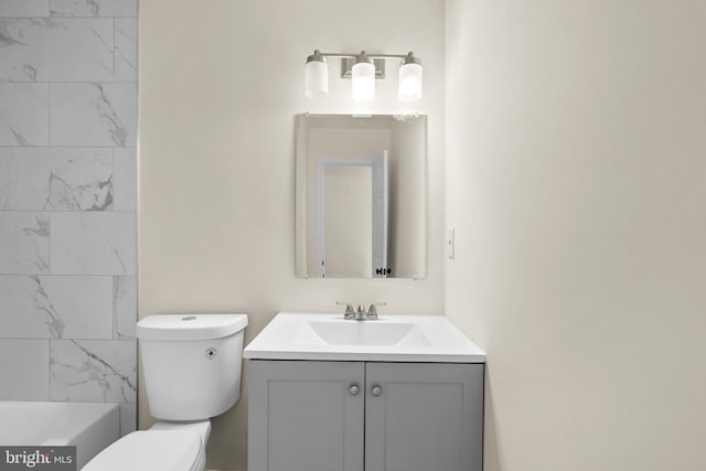 bathroom featuring vanity, a washtub, and toilet