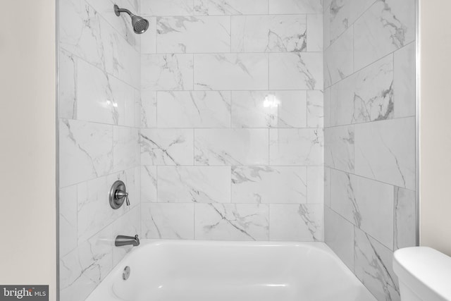 bathroom featuring tiled shower / bath and toilet