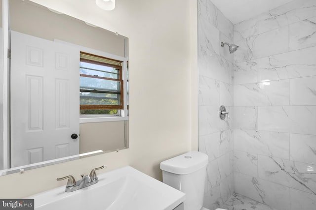 bathroom featuring tiled shower, vanity, and toilet