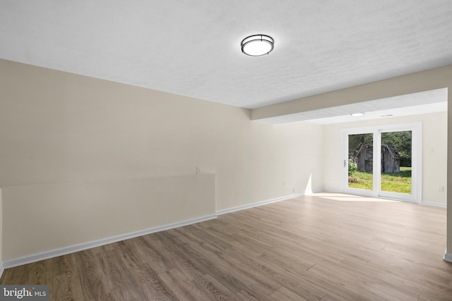 unfurnished room with a textured ceiling and light hardwood / wood-style floors