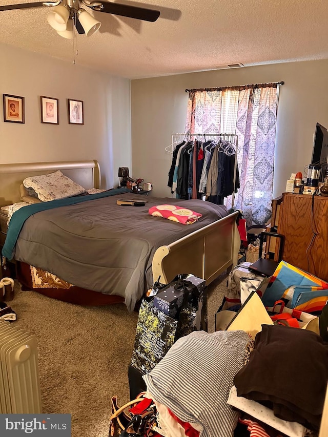 bedroom with ceiling fan, carpet, and a textured ceiling